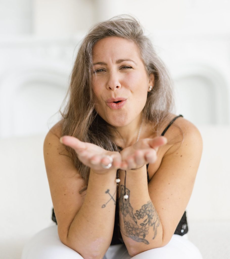 Jaime Verk smiling with hand on heart, expressing warmth, presence, and embodied connection”