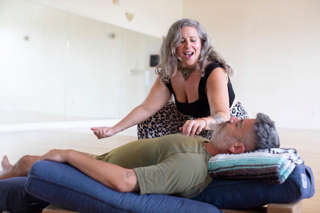Jaime Verk doing energy healing on a man in a light filled room. 